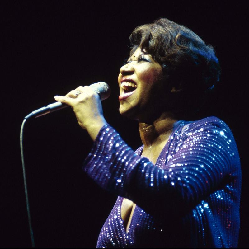 Aretha Franklin singing on stage in a blue dress