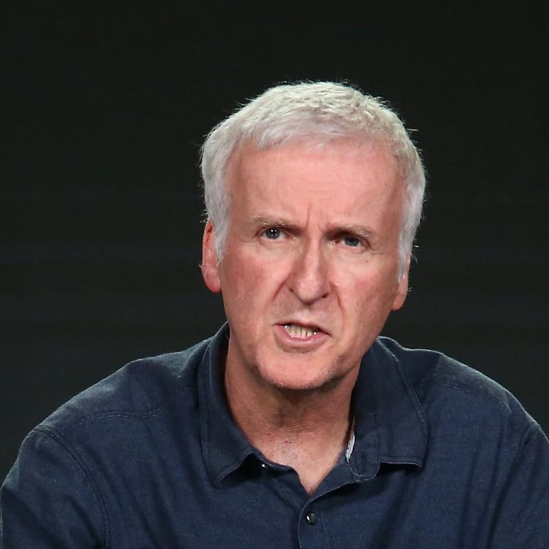 Film director James Cameron speaks on stage against a black backdrop